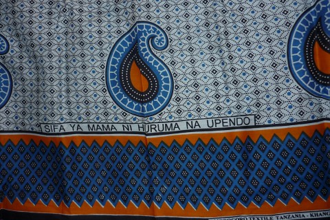 Das Foto zeigt einen weiß-blau-organge-gemusterten Kanga, ein Tuch, das in Ostafrika ein typisches Kleidungsstück ist.
