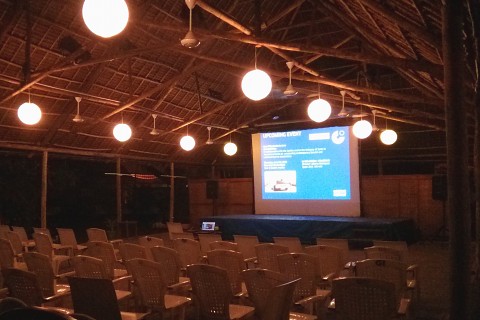 Das Foto zeigt das Freiluft-Kino des Goethe-Instituts Tansania in der Dunkelheit mit mehreren Reihen weißer Plastikstühle und einer Leinwand